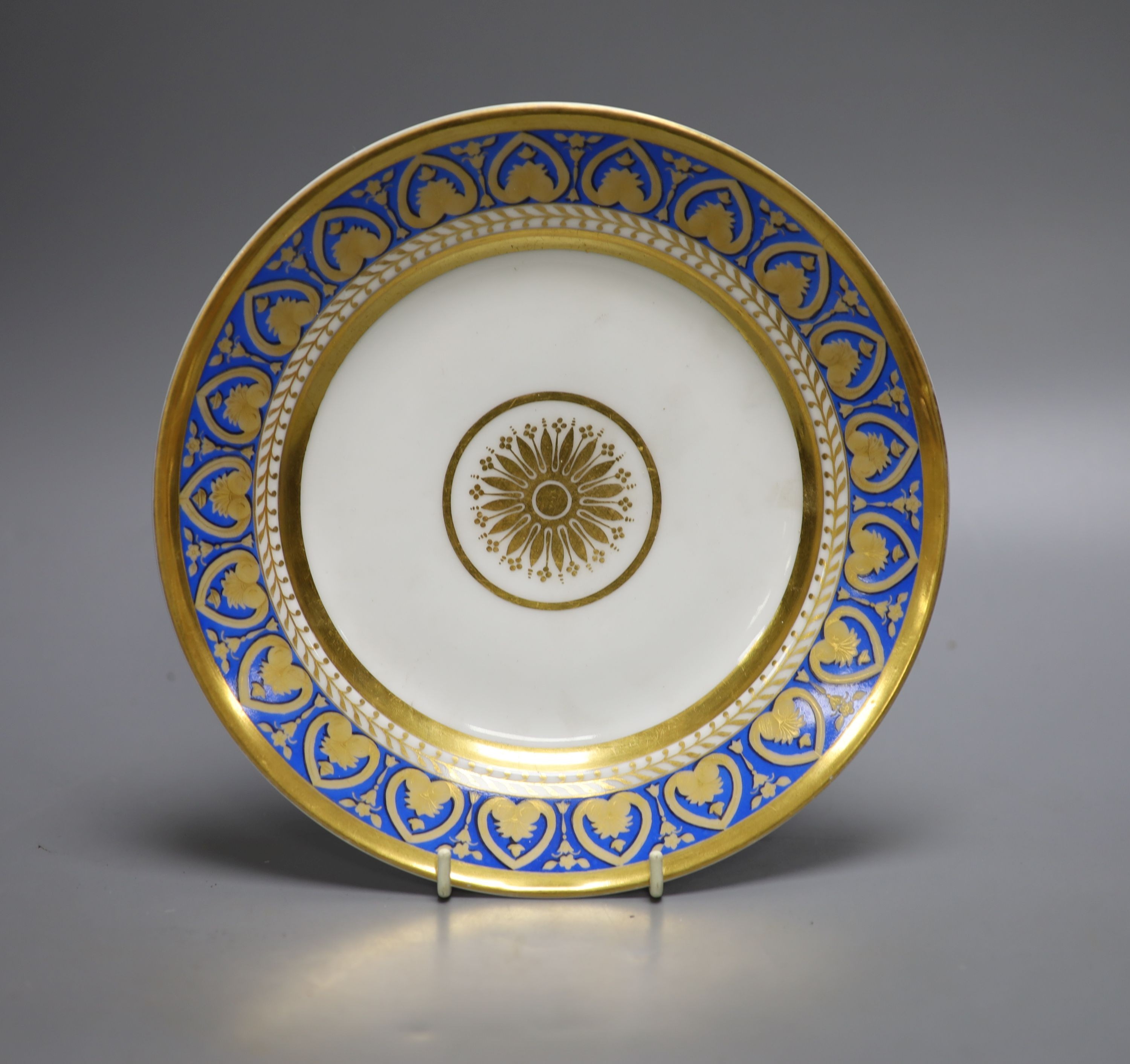 A RUSSIAN PORCELAIN PLATE IMPERIAL PORCELAIN FACTORY, PERIOD OF NICHOLAS II, In the style of the Ropsha service, with a border of gilt stylised palmettes on a blue ground dated 1912, 22cm